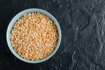 A blue plate with unprepared lentils in a dark background