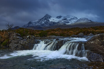 Waterfall on River Sligachan on the Isle of Skye Scotland with large mountains of the Cuillin Range in the distance with snow in winter, Isle of Skye, Scotland