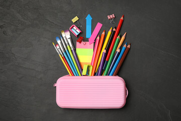Fototapeta premium Flat lay composition with different school stationery on black stone table. Back to school