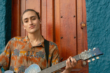 Young latin guitarist from colombia, in the center of bogota in a typical blue house of la...