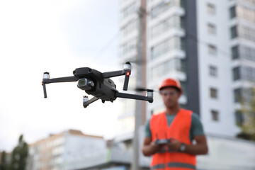 Builder operating drone with remote control at construction site. Aerial photography