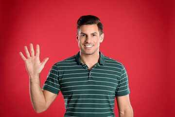 Man showing number five with his hand on red background