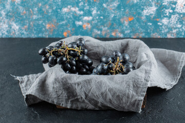 Dark fresh grape in basket on a gray tablecloth
