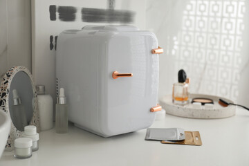 Cosmetics refrigerator and skin care products on white table indoors
