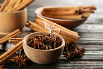 Aromatic cinnamon sticks and anise on wooden table, closeup