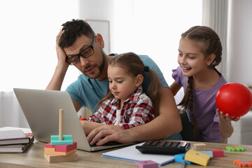 Children disturbing stressed man in living room. Working from home during quarantine