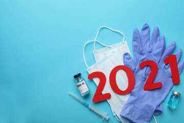 Flat lay composition with coronavirus vaccine and number 2021 on light blue background, space for text