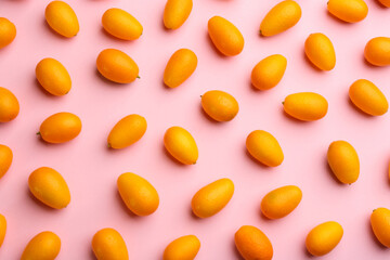 Fresh ripe kumquats on pink background, flat lay