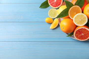 Different citrus fruits on light blue wooden table, flat lay. Space for text