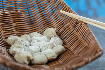 Fototapeta na wymiar A wicker basket of raw dumplings and chopsticks