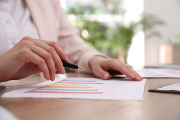 Businesswoman working with charts and graphs at table in office, closeup. Investment analysis
