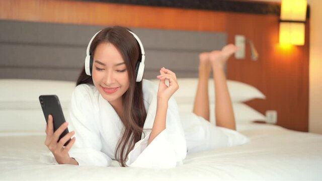 Happy Woman in Bathrobe Listening to Music on the Bed. Slow Motion.
