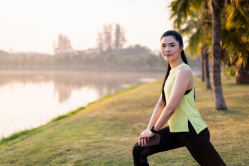 Fototapeta na wymiar Young beautiful Asian woman in sports outfits doing stretching before workout outdoor in the park in the morning to get a healthy lifestyle. Healthy young woman warming up outdoors.