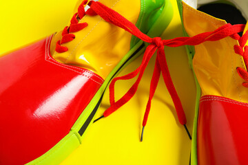 Pair of clown's shoes on yellow background, closeup