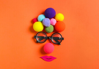 Funny face made with clown's accessories on red background, flat lay