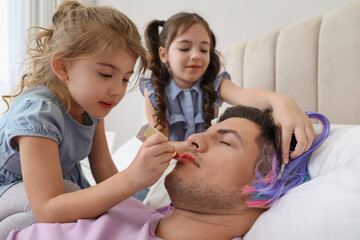 Obraz na płótnie Canvas Cute little children painting face of their father while he sleeping in bed at home