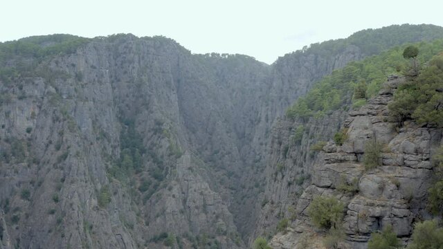 Drone video of a canyon in the rocky mountains with peaks and cliffs in a landscape city where pine trees grow .. Aerial view Antalya Turkey.