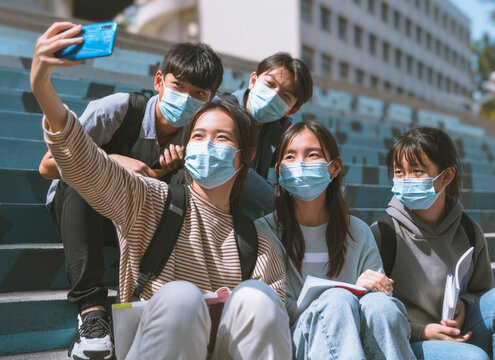young students wearing with face masks and taking selfie