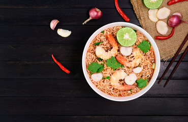 Ramen Instant Noodles in Spicy Shrimp Soup Tom Yum Kung - Asian style food. Placed on a black table with copy space, top view.