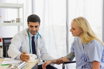 Fototapeta premium male doctor examines the symptoms of a woman is patient at working desk and talks about his illness