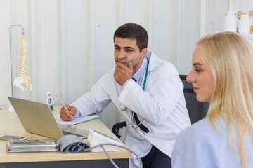 male doctor examines the symptoms of a woman is patient at working desk and talks about his illness