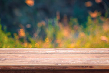 Empty wood table with bokeh yellow flowers in garden background.