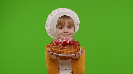 Portrait of little child girl kid dressed as professional cook chef baker with tasty strawberry pie, looking at camera on chroma key background. Concept of sweet nutrition food, cooking school