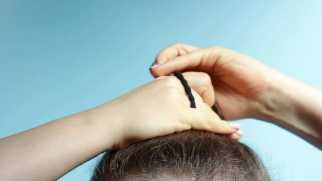 Female hand correct the bun on blue background.