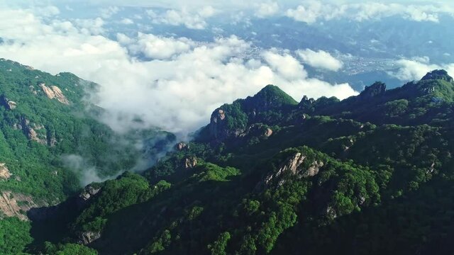 Aerial shot of white clouds over peaks and a town in Henan, China