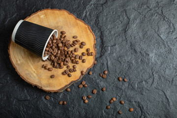 A black cup full of coffee beans on a wooden board