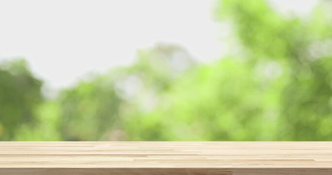 Wood table top with blur natural green foliage bokeh in background for product display mockup