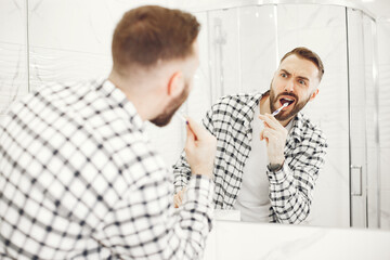 Obraz premium Man in a home bathroo. Health and well being teeth care and grooming, indoors.