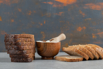 Slices of brown bread with flour on a gray backhround