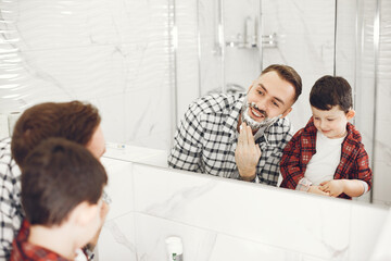 Father teaching his son to shave isolated. People with shaving foam in the bathroom.