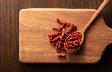 Wolfberries on a wooden spoon placed on a cutting board