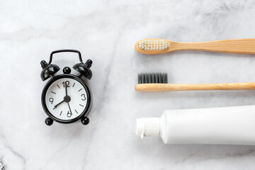 Set of eco-friendly toothbrushes and clock on marble background. Dental and healthcare concept. Top view, flat lay. - 416192346
