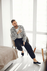 Portrait of mature man relaxing at home. Guy sittng on the chair and use the phone.