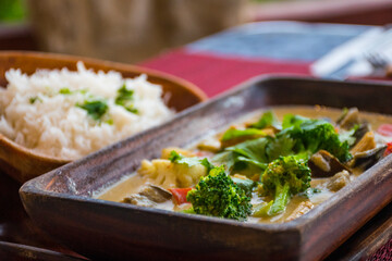 vegan cuisine with drinks on a table set for two. These healthy options are Thai Green Curry with white rice and Pad Thai. Glasses of white wine and beer are also on the candlelit table