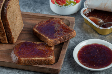 Strawberry jam with slice of brown bread and cup of tea