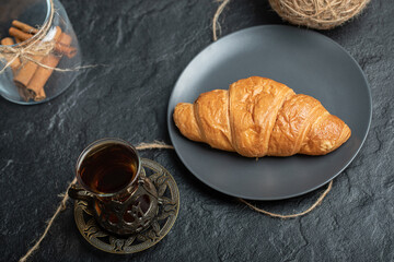 A glass jar full of cinnamon sticks with cup of tea