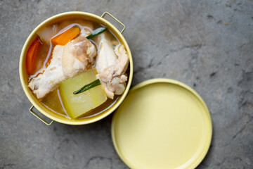 Boiled winter melon soup with chicken drumsticks and carrot in tiffin carrier for healthy food.
