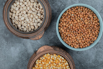 Different kinds of bean seeds, lentil, peas in dishes on a dark background
