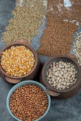 Different kinds of bean seeds, lentil, peas in dishes on a dark background