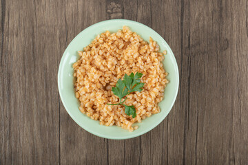 Delicious bulgur with greens on a green plate