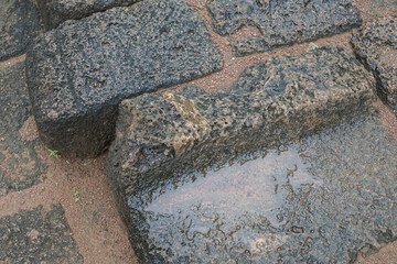 An ancient Laterite pavement at old stone ruins in Thailand on rain season.