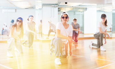 Cheerful teenagers hip hop dancers kneeling on floor during group dance workout