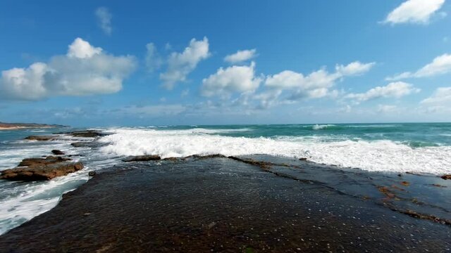 Waves crashing against rocks on the tropical gorgeous Brazilian beach of Sibauma near Pipa in Rio Grande do Norte, Brazil on a warm sunny summer day.