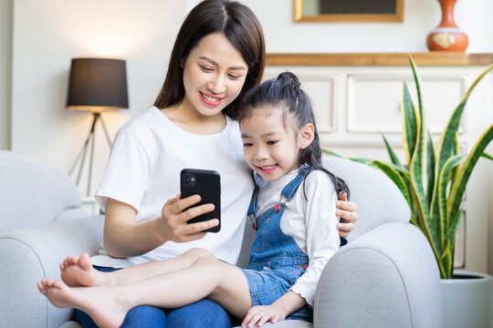 Mother and daughter are watching video on phone together while at home