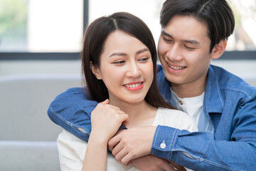 Young asian couple hugging happily at home