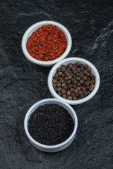 Various spices in white plates on a dark background